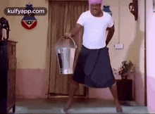 a man in a white shirt and a black skirt is holding a bucket .