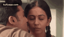 a man is kissing a woman on the forehead with his eyes closed .