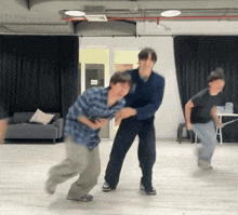 a man in a blue plaid shirt is holding another man 's arm