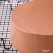 a cake with chocolate frosting is being poured on a cooling rack