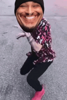a man wearing a beanie and a floral shirt is dancing with a face on his head