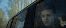 a man is sitting in a car looking out the window .