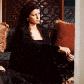 a woman in a black dress sits on a couch