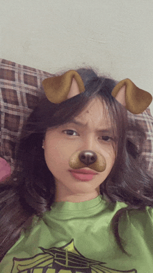 a girl wearing a green shirt has a dog 's nose on her face