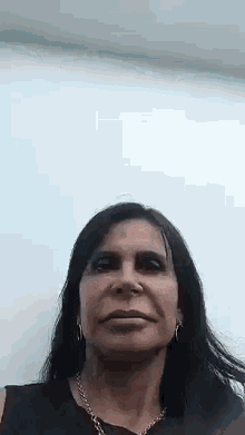 a woman with long black hair and a nose ring is smiling and looking at the camera .