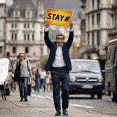 a man in a suit holds a sign that says stay #