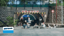 a group of people sit under a sign that says 2.5m
