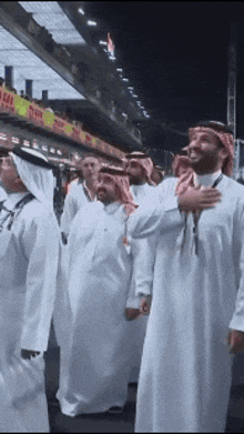 a group of men in white robes are standing in front of a building that says ' dubai ' on it