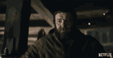 a man with a beard is in a dark room with a netflix logo behind him