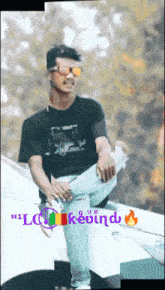 a man wearing sunglasses and a black shirt is sitting on the hood of a car with the word kevind written below him