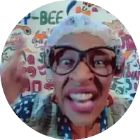 a woman with glasses and a moustache is smiling in front of a wall that says beef