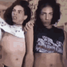 a man and a woman are standing next to each other and one of them is taking off his shirt .