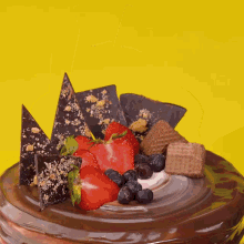 a chocolate cake with strawberries blueberries and wafers on top