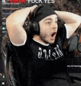 a man wearing headphones and a headband is sitting in a chair with his hands on his head .