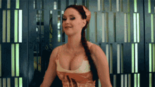 a woman with a braided hair and a huge breast stands in front of a striped wall