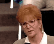 a woman with red hair and glasses is speaking into a microphone