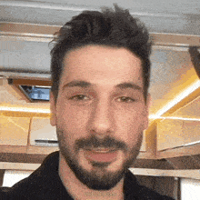 a close up of a man 's face with a beard and a black shirt .
