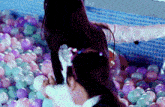 a woman and child are playing in a ball pit filled with colorful balls