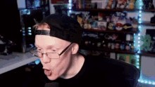 a man wearing glasses and a baseball cap is making a funny face