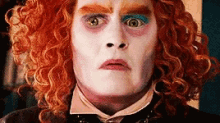 a close up of a man 's face with red curly hair and colorful makeup .