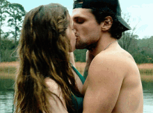 a man and woman kissing in front of a lake