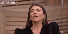a woman in a black dress and hoop earrings is making a face .