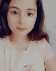 a young girl in a pink shirt is taking a selfie with her eyes closed .