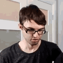 a young man wearing glasses is making a funny face .