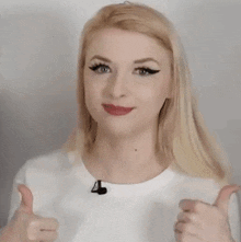 a woman is smiling and giving a thumbs up sign .