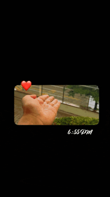 a person 's hand is shown with a red heart above it and the time is 6:55 pm