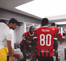 a group of soccer players are in a locker room and one of them has the number 80 on his shirt