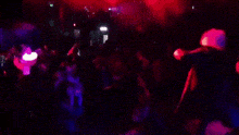 a group of people are dancing in a dark room with red lights