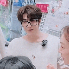 a man wearing glasses and a white sweater is standing next to a woman .