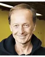 a close up of a man 's face smiling and wearing a black sweater .