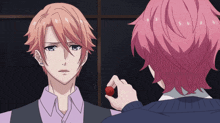 a man with pink hair is looking at another man holding a red object