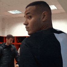 a man in a black and white shirt is standing in a locker room
