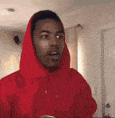 a man wearing a red hoodie is looking at the camera