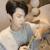 a man in a sweater is holding a tape measure in his hand .