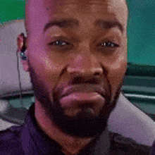 a man with a beard and ear buds is making a funny face while sitting in a car .