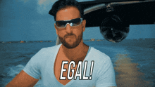 a man wearing sunglasses and a white shirt has the word egal written on his chest