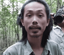 a man with a beard is holding a canon camera