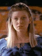 a woman with blonde hair wearing a blue shirt