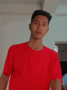 a young man in a red shirt is making a funny face with the words goli handim written on his shirt .
