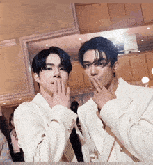 two men in white suits are posing for a photo