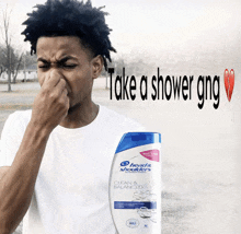 a man is holding his nose next to a bottle of head & shoulders shampoo