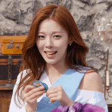 a woman with red hair is smiling while holding a blue object