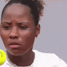 a close up of a woman 's face with a tennis ball in the foreground .