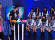 a group of girls are sitting on a bench in front of a man