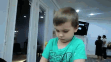 a young boy wearing a green shirt with the word comp on it .