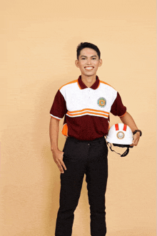 a man wearing a maroon and white shirt holds a white helmet